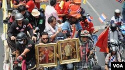 Demonstran anti-pemerintah Kaos Merah, membawa gambar raja dan ratu Thailand, meninggalkan perkemahan mereka di kawasan perdagangan kota Bangkok, 28 April 2010.