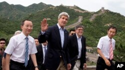 U.S. Secretary of State John Kerry, center, and U.S. Treasury Secretary Jacob Lew, second from right, wave to journalists as they visit to Badaling Great Wall of China in Beijing, China, July 8, 2014. 