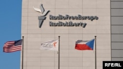 FILE - Signage is seen on the headquarters building of Radio Free Europe/Radio Liberty (RFE/RL), with the United States, RFE/RL and the Czech Republic's flags fluttering in the foreground, in Prague. (Jan Rambousek - RFE/RL)
