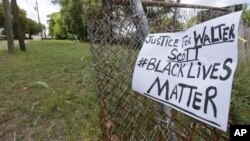A sign calling for justice is attached to a fence near the site where Walter Scott was killed in North Charleston, S.C., Wednesday, April 8, 2015.
