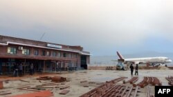 Nepalese residents stand near the domestic terminal building, after a domestic plane crashed in the northwest of Kathmandu valley in Kathmandu, Nepal on Feb. 16, 2014.