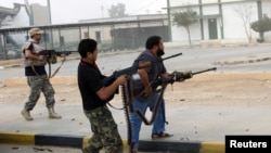 Militia fighters are seen shooting at a building in center of Bani Walid, Libya, October 24, 2012. 