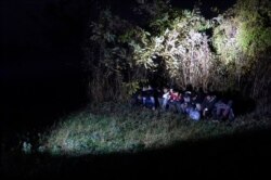 In this photo taken Saturday, Nov. 9, 2019, Bosnian border police officers guard migrants after making the illegal crossing from Serbia by the Drina river, the natural border between Bosnia and Serbia, near eastern Bosnian town of Zvornik, Bosnia…