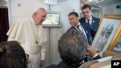 Pope Francis receives a gift from a journalist during his flight from Abu Dhabi to Rome, Feb. 5, 2019.
