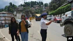 A traffic policewoman wearing a face mask controls the flow of traffic in Kohima, capital of the northeastern Indian state of Nagaland, May 29, 2020. 
