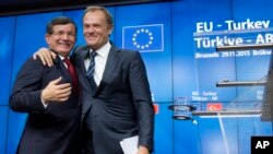 PM Turki Ahmet Davutoglu (kiri) berangkulan dengan Presiden Uni Eropa Donald Tusk pada KTT 4 jam di Brussels, Belgia Minggu (29/11).