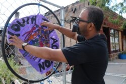 Ruhel Islam fixes a sign near the ruins of Gandhi Mahal Restaurant. (K. Khan/VOA)