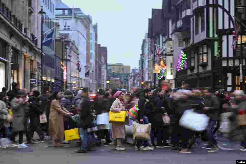 Shoppers cross the street on Regent St during Boxing Day sales, in London.