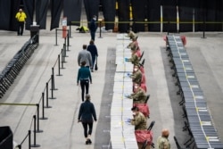 FILE - People walk through a new COVID-19 rapid testing site operated by the Rhode Island Army National Guard, in Providence, Rhode Island, Dec. 1, 2020.