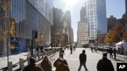 Pedestrians walk along Greenwich Street next to 4 World Trade Center (L) in New York, Nov. 13, 2013.