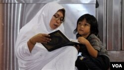 Seorang perempuan membacakan Al-Quran kepada anaknya di sebuah sore di Masjid Istiqlal, Jakarta (foto: dok).