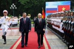 Presiden Rusia Vladimir Putin (tengah) bersama Presiden Vietnam To Lam memeriksa barisan pengawal kehormatan saat upacara penyambutan resmi di Istana Kepresidenan Vietnam, di Hanoi, Kamis, 20 Juni 2024. (Gavriil Grigorov, Sputnik, Kremlin Pool Photo via AP)