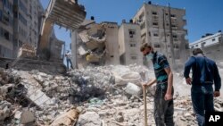 Peralatan berat digunakan untuk membersihkan puing-puing bangunan yang hancur akibat serangan udara Israeli di Kota Gaza sebelum gencatan senjata mengakhiri konflik senjata antara Gaza dan Israel, 27 Mei 2021.