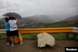 Residents affected by Hurricane Maria stand atop a mountain where mobile service was available near the municipality of Orocovis, outside San Juan, Puerto Rico, Oct. 10, 2017.