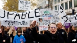A woman raises her fist as she and thousands of others protest against domestic violence, in Paris, Nov, 23, 2019. 