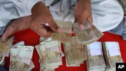 A Pakistani money changer counts Pak rupees in Karachi, Pakistan on Oct 24, 2008.