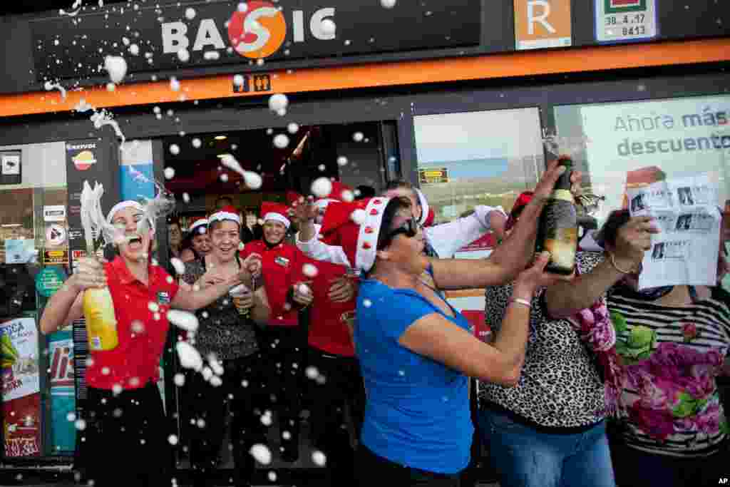 Para pekerja sebuah pom bensin bergembira bersama teman dan pelanggan setelah memenangkan lotere Natal &ldquo;El Gordo&rdquo; (&ldquo;Si Gendut&quot;) di Santa Cruz de Tenerife di Kepulauan Canary, Spanyol (22/12). (AP/Andres Gutierrez)