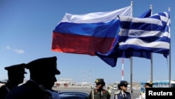 FILE - Greek police and army officers stand by Greek, Russian and EU flags as they wait for the arrival of Russian President Vladimir Putin at Athens' airport, May 27, 2016.