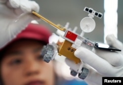 FILE - A worker inspects a scale model of the moon rover for China's Chang'e 4 lunar probe, at a factory in Dongguan, Guangdong province, China, Nov. 16, 2018.