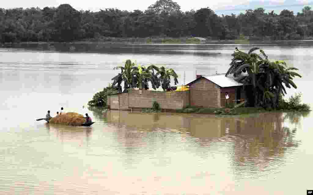 Indian villagers row through their flooded village in a small boat, in northeastern Assam state, India, Aug. 18, 2014.