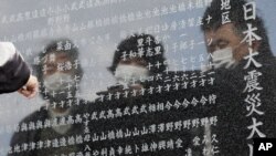 A man points to the name of one of the victims of the earthquake and tsunami inscribed in a cenotaph in Okawa district in Ishinomaki, Miyagi Prefecture, northern Japan, March 11, 2013.