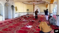 Sejumlah jurnalis memotret dan mengambil gambar di dalam sebuah masjid setelah ledakan di distrik Shakar Dara, di Kabul, Afghanistan, 14 Mei 2021. (Foto: Rahmat Gul/AP)