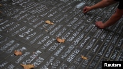 A person writes messages on a sidewalk at Las Ramblas in Barcelona, Spain, Aug. 19, 2017.