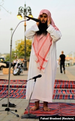 A member of the Committee for the Promotion of Virtue and Prevention of Vice, or religious police, calls for prayers on a street outside coffee shops in Riyadh June 27, 2010.