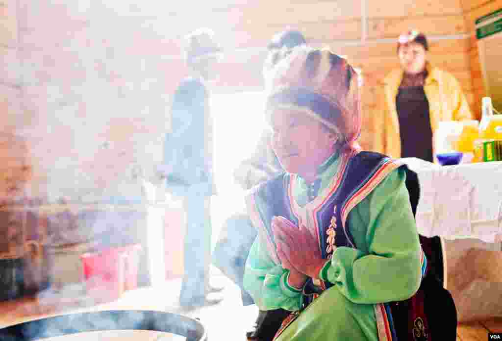 In a high mountain yurt, a woman elder from the Kun community burns juniper twigs in a shamanistic purification and blessing welcome ceremony for foreign visitors. (Vera Undritz for VOA)
