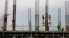 FILE - Construction workers stand on scaffolding around metal rods of a new pillar as they add more floors to a building project in suburban Paranaque city, south of Manila, Philippines, Jan. 26, 2017. 