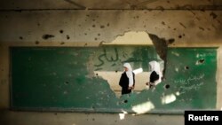 Palestinian students look inside a classroom that witnesses said was shelled by Israel during its offensive, on the first day of the new school year east of Gaza City September 14, 2014.