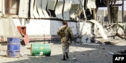 FILE - Members of the Yemeni pro-government forces walk through destruction in an industrial district in the eastern outskirts of the port city of Hodeida on Nov. 18, 2018, during the ongoing battle for control of the city from the Houthi rebels.