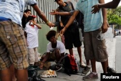 Youths eat a cake they'd found in a trash bag in Caracas, Venezuela, Feb. 27, 2019.