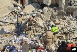 FILE - Civil defense members search for survivors at a site hit by what activists said were airstrikes carried out by the Russian air force in Idlib city, Syria, Dec. 21, 2015.