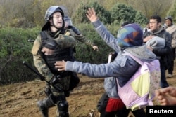 A Macedonian police officer hits a stranded migrant attempting to cross the Greek-Macedonian border, near Gevgelija, Macedonia December 2, 2015.