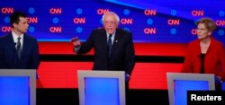 ete Buttigieg (L) and U.S. Senator Elizabeth Warren (R) watch U.S. Senator Bernie Sanders