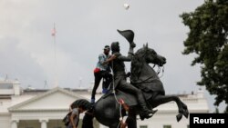FILE - Protesters attach a chain to the statue of President Andrew Jackson to pull down in the middle of Lafayette Park outside the White House as someone throws a roll of toilet paper during racial inequality protests in Washington, D.C., June 22, 2020.