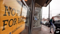 FILE - A woman passes by a "No Place For Hate" sign in a shop in Pittsburgh's Squirrel Hill neighborhood, Feb. 11, 2019.