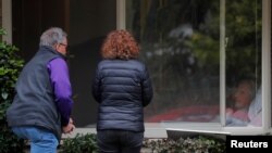 22일 미국 워싱턴주 커클랜드에 있는 요양센터 '라이프케어 센터'에서 코로나19 확진자가 창문 너머로 가족과 인사하고 있다.