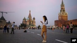 FILE - A young woman checks her smartphone at Red Square in Moscow, Russia, July 2016. (AP Photo/Pavel Golovkin)