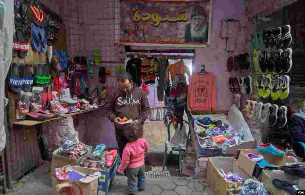 A father buys shoes for his daughter ahead of Christmas. (Hamada Elrasam/VOA) 