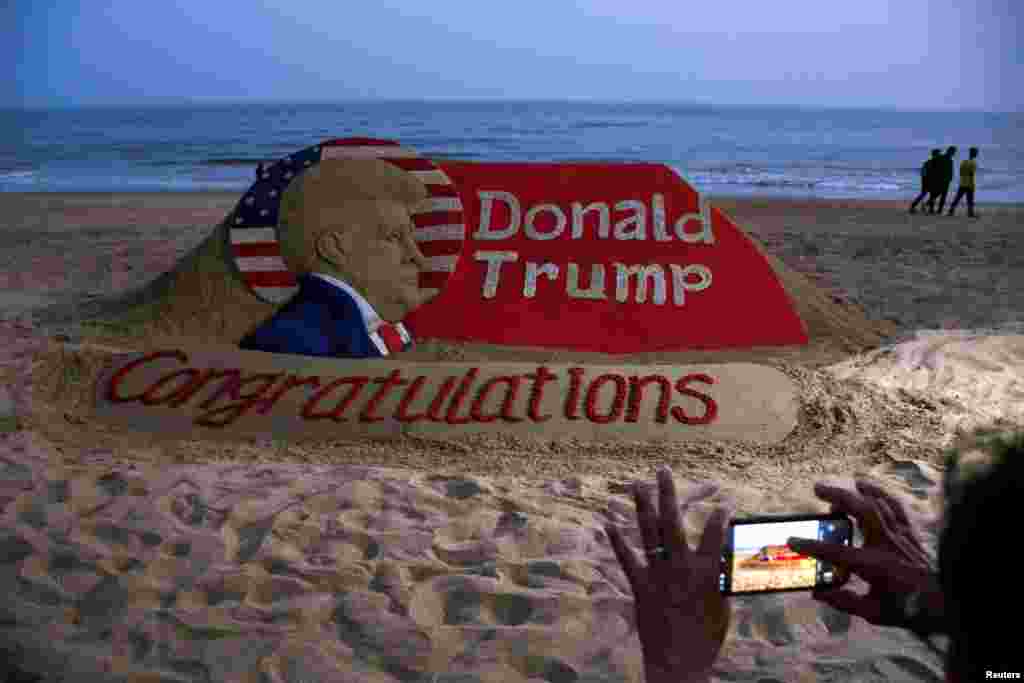 A person takes a picture of a sand sculpture depicting Republican Donald Trump after he won the U.S. presidential election, at Puri beach, in the Eastern State of Odisha, India, Nov. 6, 2024.