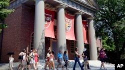 FILE - A tour group walks through the campus of Harvard University in Cambridge, Mass, Aug. 30, 2012. The Justice Department has sided with Asian-American students suing Harvard University over the Ivy League school's consideration of race in its admissio