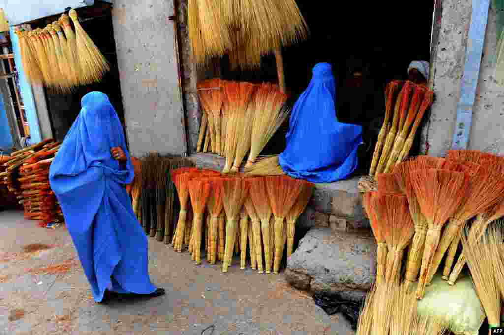 Afghan shoppers look for brooms at a roadside shop in Herat.