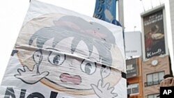 Anti-nuclear demonstrators wearing protective suits march down streets in Tokyo, Japan, June 11, 2011