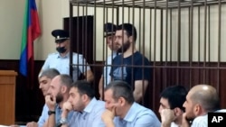 In this photo taken on Sunday, June 16, 2019, Abdulmumin Gadzhiev, the religious affairs editor of the independent weekly Chernovik, stands in a cage in a court room in Makhachkala, the Caspian Sea province of Dagestan, Russia, Sunday, June 16, 2019.