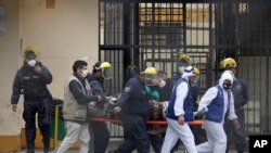 Inmates wearing white protective suits, and security agents, transport an inmate to a clinic at the Lurigancho prison on the outskirts of Lima, Peru, Aug. 19, 2020. 