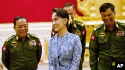 Myanmar's NLD party leader Aung San Suu Kyi smiles with army members during the handover ceremony of outgoing President Thein Sein and new President Htin Kyaw at the presidential palace in Naypyitaw, March 30, 2016. 