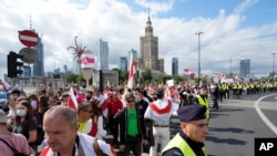People carry Belarusian flags denouncing the regime of Belarusian President Alexander Lukashenko during a rally in support of the country's opposition, in Warsaw, Poland, Aug. 8, 2021. 