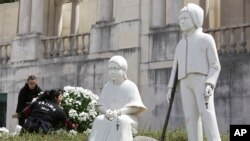 Deux femmes déposant des fleurs près des statues de Jacinta et Francisco, sanctuaire de Fatima, Portugal, le 11 mai 2017. (AP Photo/Armando Franca)